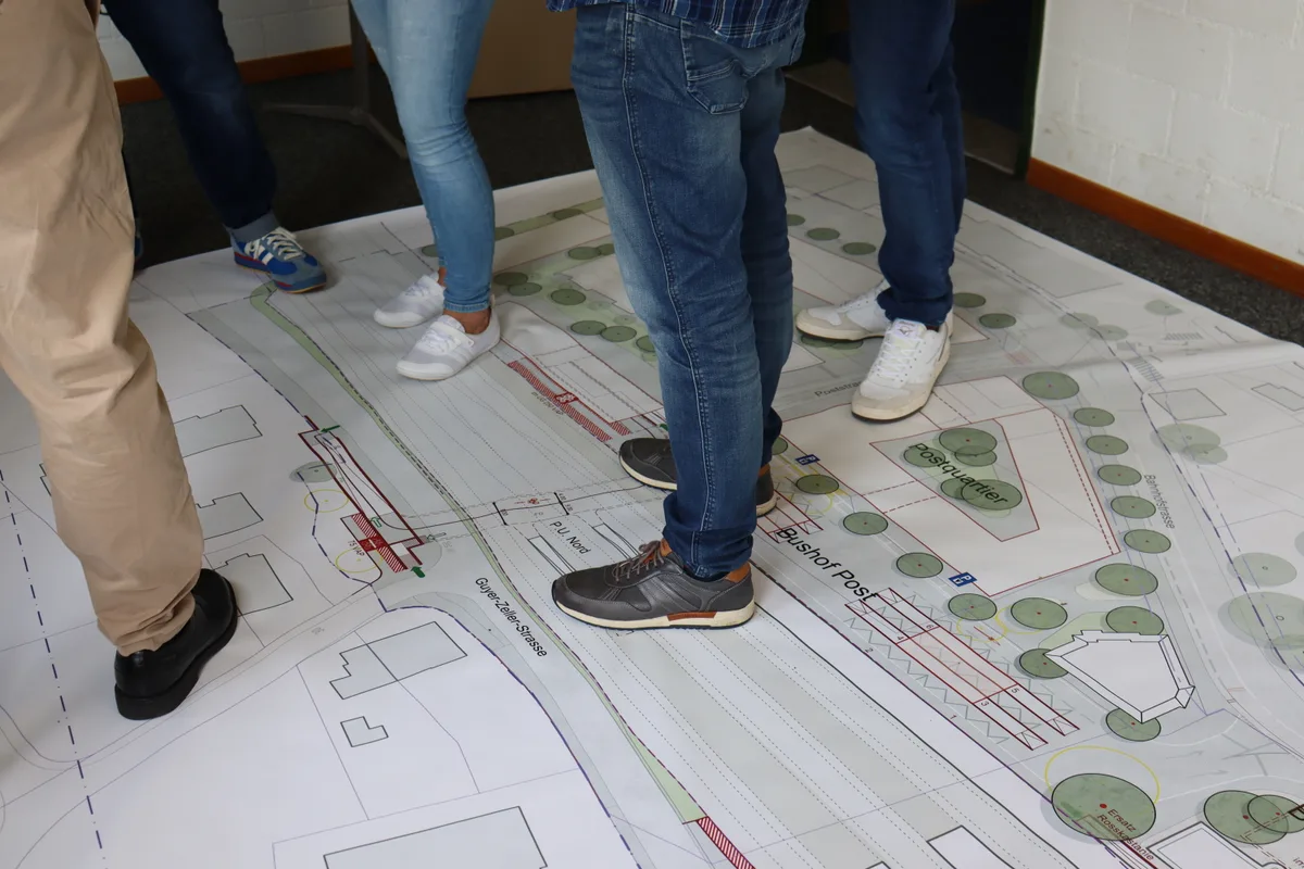 Menschen stehen auf grossem Situationsplan vom Bahnhof